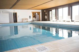 a large swimming pool with chairs and a table at Hotel Bayerischer Wald in Neukirchen