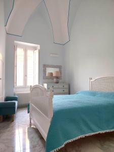 a bedroom with a white bed with a blue bedspread at Suite in centro in Galatina