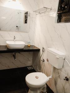 a white bathroom with a toilet and a sink at Casa De Menorah in Nerul
