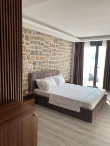 a bedroom with a bed and a brick wall at Agape Rose in Tivat