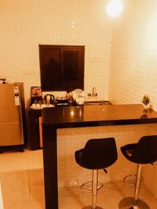 a kitchen with a counter and two bar stools at Casa De Menorah in Nerul
