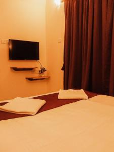 a bedroom with a bed with a television on the wall at Casa De Menorah in Nerul