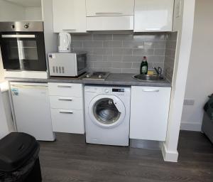 a kitchen with a washing machine and a sink at The Serviced Accommodations in Harlow