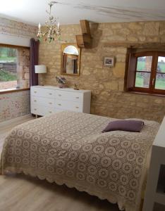 - une chambre avec un lit et un mur en pierre dans l'établissement Sublime Maison avec Piscine en Dordogne, à Clermont le-Vialard