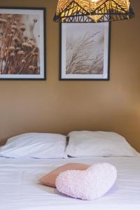 - un oreiller en forme de cœur sur un lit avec 2 photos dans l'établissement AmorAmor ~ T2 Romantique, à Vierzon