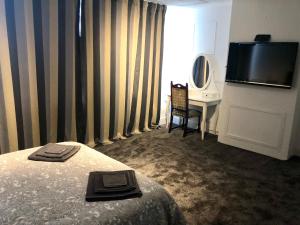 a hotel room with a bed and a desk and a television at AC Lounge 125 in Rochford