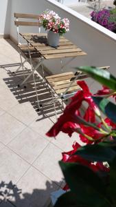 a table and a bench with flowers on a porch at Lovely House risveglio fronte mare in Marina di Pescoluse