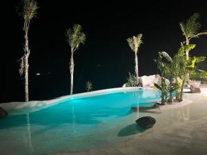 una piscina azul con palmeras por la noche en Finca el atardecer - Apartamento Sol, en Los Santos de Maimona