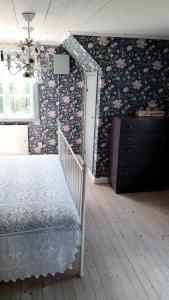 a bedroom with a bed and a dresser with floral wallpaper at Lunden in Vittaryd