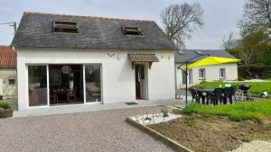 een wit huis met een tafel en stoelen bij La Bourgandie in Englesqueville-la-Percée