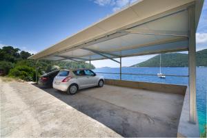 a small car parked under a large building next to a body of water at Apartments Marija in Brna +117 photos