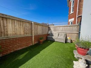 um pequeno quintal com uma cerca e um sofá em Woodside Road, Southbourne em Bournemouth