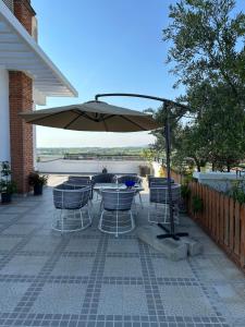 a patio with a table and chairs under an umbrella at Hotel New York in Kamëz