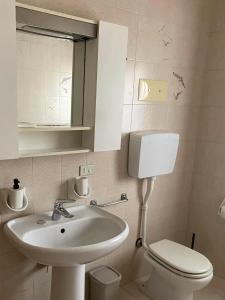 bagno con lavandino, servizi igienici e specchio di LA DIMORA DELL'ARTISTA a San Zeno