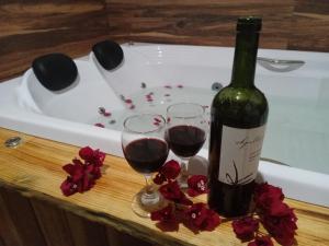 una bottiglia di vino e due bicchieri in una vasca da bagno di Recanto KAIRÓS a Visconde De Maua
