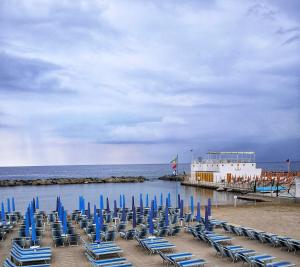 a group of blue chairs on a beach with a boat at Casa Matuzia in Sanremo