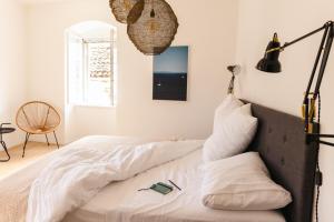 um quarto com uma cama com lençóis brancos em Pomalo Inn em Vis