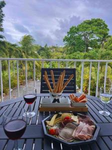 einen Tisch mit einem Teller Essen und zwei Gläsern Wein in der Unterkunft La Verdure in Petit-Bourg