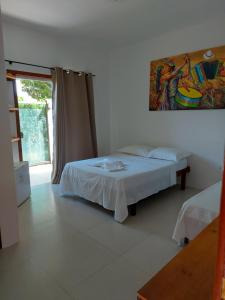 a bedroom with a bed and a painting on the wall at Pousada Mirante de Areia-Itaúnas in Itaúnas