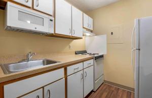 a kitchen with white cabinets and a sink and a refrigerator at Extended Stay America Suites - Cincinnati - Blue Ash - Reagan Hwy in Blue Ash