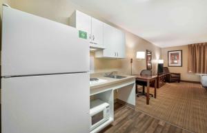 a kitchen with a refrigerator and a living room at Extended Stay America Suites - Fort Wayne - South in Fort Wayne