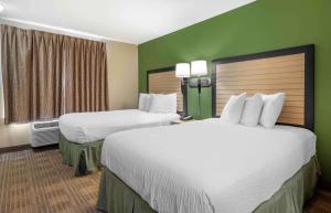 two beds in a hotel room with green walls at Extended Stay America Suites - Cincinnati - Blue Ash - Kenwood Road in Blue Ash