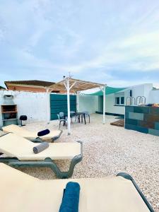 eine Terrasse mit Stühlen, einem Picknicktisch und einem Gebäude in der Unterkunft Casita de la coquina in Chiclana de la Frontera