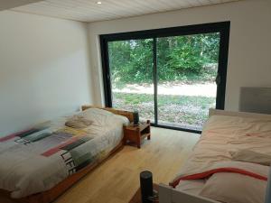 a bedroom with two beds and a large window at La maison du bois, 10 minutes de l'A71, 10 minutes de Bourges in Plaimpied-Givaudins