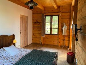 ein Schlafzimmer mit einem Bett in einer Holzhütte in der Unterkunft Skansen Pomezania in Kałduny