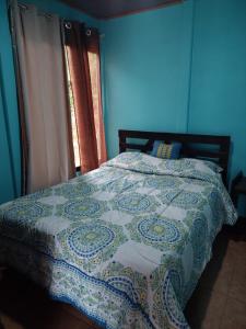 a blue bedroom with a bed with a quilt on it at Jessie's Country House Rivas in Rivas
