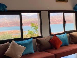 petite jolie maison vue sur lac في بين الويدان: أريكة مع وسائد يجلسون في غرفة مع نوافذ