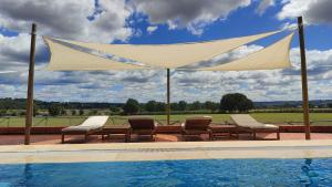 un dosel sobre una piscina con sillas, una mesa y una piscina en Quinta das Arribas, en Abrantes