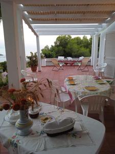 un tavolo con tavoli e sedie bianchi su un patio di Villa Eminenza a Cersuta di Maratea