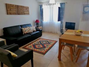 a living room with a black couch and a table at Apartamento Praiamar in Vila Nova de Milfontes