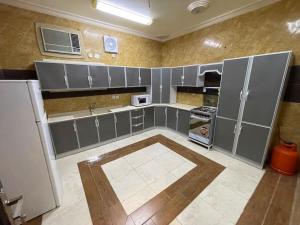 a large kitchen with gray cabinets and a refrigerator at شقة واسعة بفناء خاص و دخول ذاتي in Al Madinah
