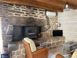 een stenen open haard in een kamer met stoelen en een televisie bij Ty Auguste, petite maison bretonne in Plobannalec-Lesconil