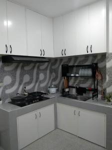 una cucina con armadi bianchi e lavandino di 80Square Guest House a Gingoog