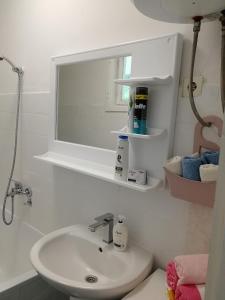 a white bathroom with a sink and a window at Apartman Mušinbegović in Visoko