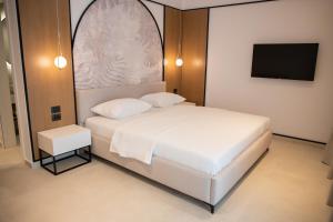 sypialnia z białym łóżkiem i telewizorem z płaskim ekranem w obiekcie Colosseum Hotel w mieście Ksamil