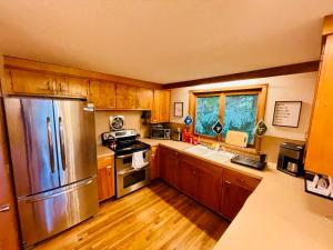 a kitchen with wooden cabinets and a stainless steel refrigerator at Contemporary Magic Mountain Chalet Close to Skiing, Hiking, Fun in Londonderry