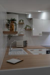 uma cozinha com armários brancos e um lavatório em Lotfnazarewaves na Nazaré