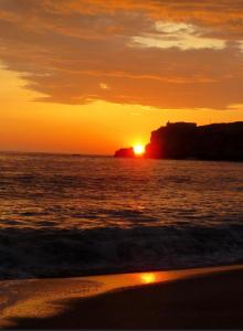 um pôr do sol na praia com o pôr do sol em Lotfnazarewaves na Nazaré