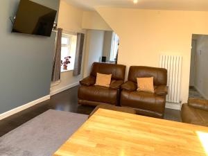 a living room with two brown leather couches and a table at Greenwood in Manchester