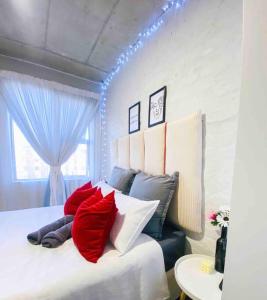 1 dormitorio con 1 cama con almohadas rojas y blancas en Cozy escape bachelor in Maboneng + uncapped WI-FI., en Johannesburgo