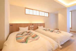 two white beds in a bedroom with a window at Yuyado Mikannoki in Atami