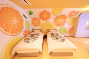 two beds in a room with orange slices on the wall at Yuyado Mikannoki in Atami