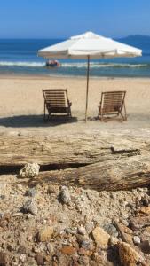 two chairs and an umbrella on a beach at Shambhala Quarto Ecológico Beira Mar entre Paraty e Ubatuba in Ubatuba