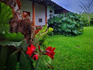 a house with red flowers on the side of a yard at Hacienda El Samán in Quimbaya