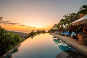 una piscina en un complejo con sillas y una puesta de sol en Villa Selonding Batu, en Lovina