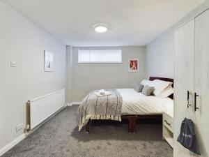 a white bedroom with a bed and a window at Luxury Accommodation with TVs in each Room in Macclesfield